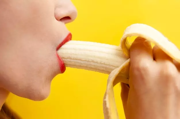 Red blowjob lips enclose a banana